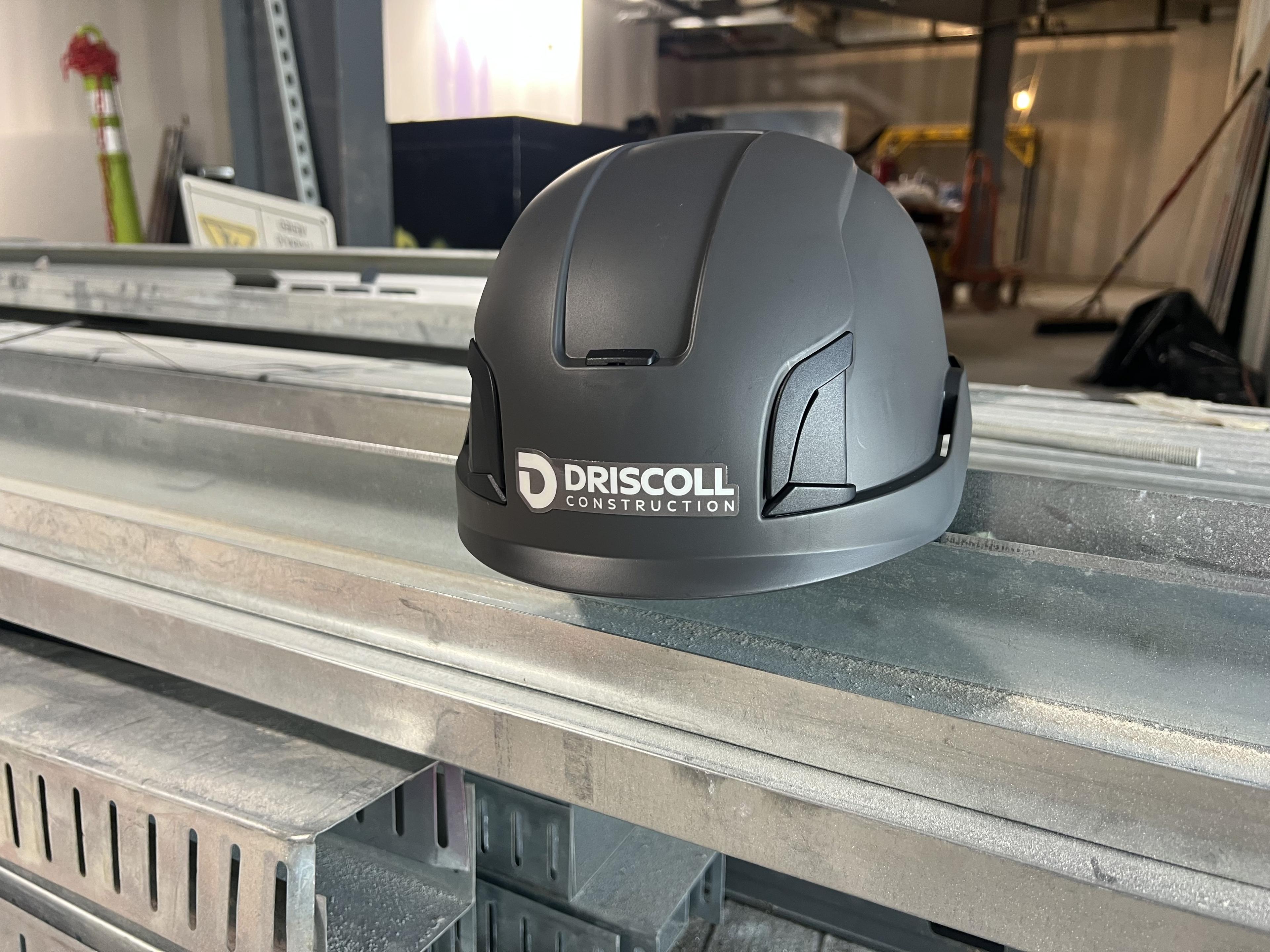 Driscoll Construction branded helmet in an active construction environment